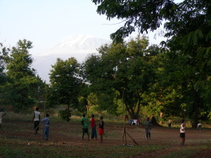 Soccer in Africa.  No grass, no nets, tattered ball, some have shoes.  Still fun!